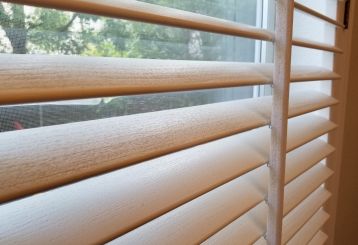 Bedroom with wooden blinds for windows.